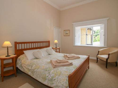 a bedroom with a bed with two chairs and a window at The Old Nursery in Much Wenlock