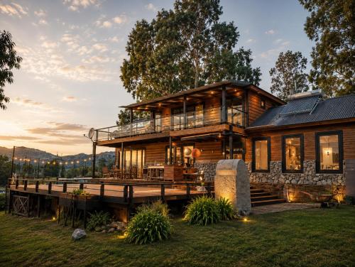 a log cabin with a deck and a house at Cabañas Valle de los Ciervos in Tandil