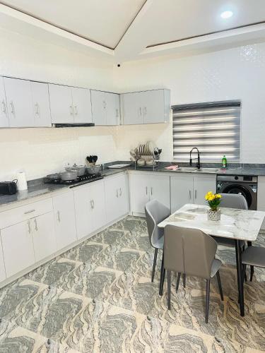 a kitchen with white cabinets and a table and chairs at DAS Apartments Lugbe in Abuja