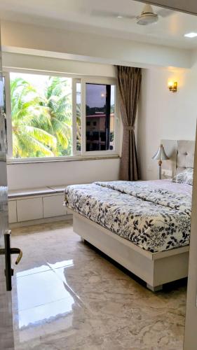 a bedroom with a bed and a large window at The Palm Retreat Luxe 1bhk Near Thivim Station in Advolpale
