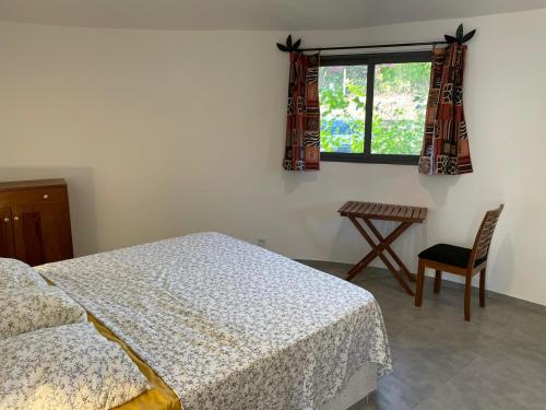 a bedroom with a bed and a table and a window at Les Cases Rouges in Kaolack