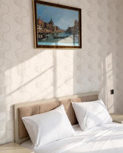 a bed with two pillows and a painting on a wall at Bilgah Coast Villa in Baku