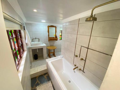 a bathroom with a tub and a sink at Guesthouse 1921 in Hartbeespoort