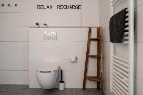 a white bathroom with a toilet and a ladder at Shaft by Loftigo - Apartment mit Wellnessdusche in Übach-Palenberg