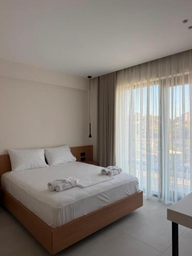 a bedroom with a large bed and a large window at Soléa Himara Guesthouse in Himare