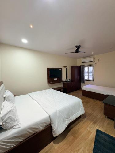a bedroom with a large white bed and a flat screen tv at TSR Grand Hotel in Bhogāpuram