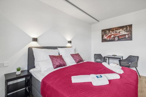 a bedroom with a large red bed with two chairs at Studio Apartment Dietzenbach in Dietzenbach