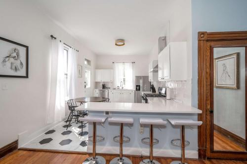 a white kitchen with a counter and some chairs at Historical John H Dickman House in Covington