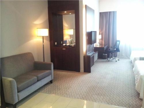 a hotel room with a couch and a bed and a television at Raia Hotel & Convention Centre Alor Setar in Alor Setar
