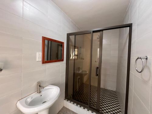 a bathroom with a shower and a sink at Nduna Legacy Lodge in Harare