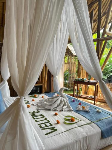 a white bed with white curtains and flowers on it at Bamboo Garden Villa Sidemen - Private Pool & Nature View in Selat