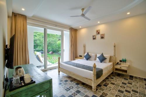 a bedroom with a bed and a large window at The Goa Courtyard by Forever stays in Arpora