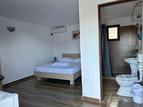 a bedroom with a bed and a sink and a toilet at Vila Elna in 2 Mai