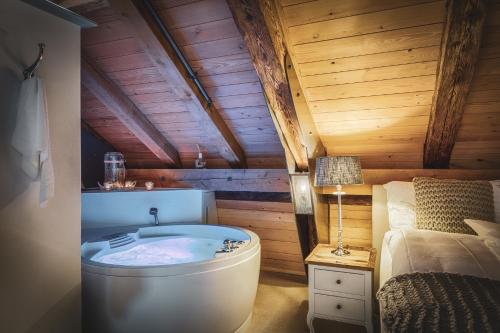 a bathroom with a tub in a room with a bed at Romantik Hotel Bären Dürrenroth in Dürrenroth