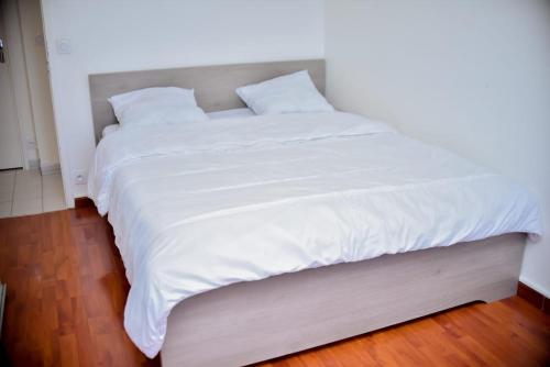 a large white bed with white sheets and pillows at super apparemment pour vos vacances in Neuilly-sur-Marne