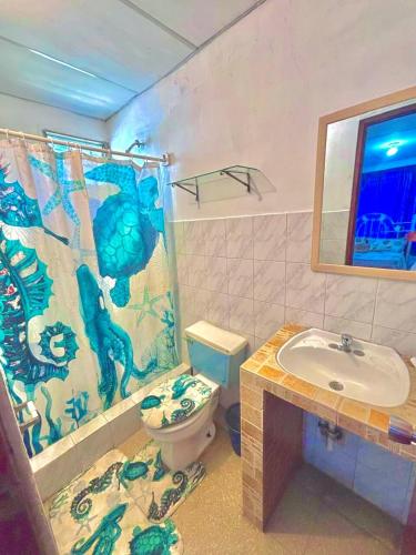 a bathroom with a toilet and a sink and a shower curtain at Cabana Steps From The Beach - Pool & Beach Access in Nueva Gorgona