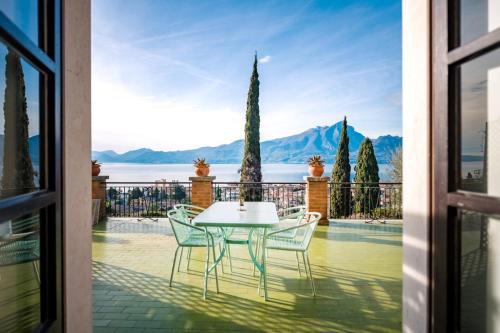 a table and chairs on a balcony with a view of the water at Villa Maria Lake View,7 minuti a piedi dal centro, parcheggio privato in Torri del Benaco