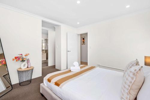 a white bedroom with a large bed in a room at 4 bedroom luxury modern home near the beach and parks in Alkimos