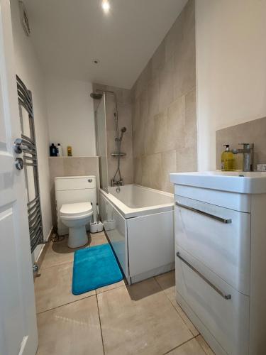 a bathroom with a toilet and a tub and a sink at Serene 2-BDR Maisonette in Wolverhampton