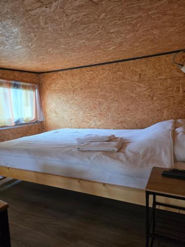 a bedroom with a white bed with a wooden wall at Poddasze in Zblewo