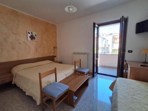 a bedroom with two beds and a table and a window at Hotel Edelweiss in Laino Borgo
