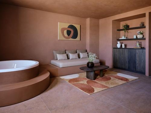 a bathroom with a tub and a couch and a table at Oroséa Paros - Adults Only, Autograph Collection in Naousa