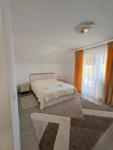 a white bedroom with a bed and a window at Chill Garden House in Satu Mare