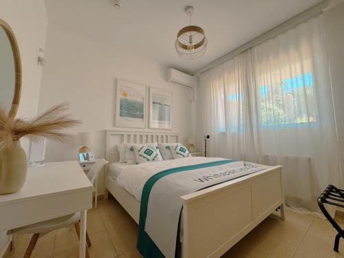 a white bedroom with a bed and a desk at Whitealcyone Fit & Zen Apartment in Artemida