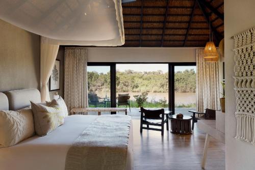 a bedroom with a large bed with a large window at Lion Sands River Lodge in Sabi Sand Game Reserve