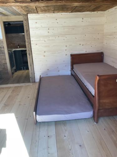 a bed in a room with a wooden floor at Le vieux chalet in La Forclaz