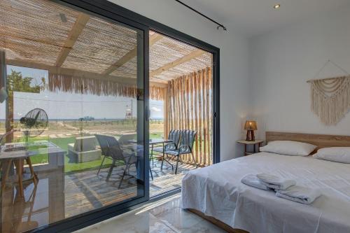 a bedroom with a bed and a balcony with a table at Almond Beachfront Resort - kalyves Halkidiki in Kalives Poligirou