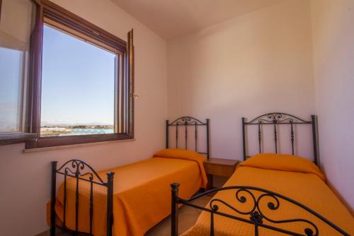 2 camas con sábanas de color naranja en una habitación con ventana en Appartamenti Elios en Birgi Vecchi