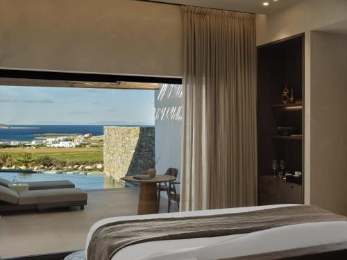 a bedroom with a large window with a view of the ocean at Oroséa Paros - Adults Only, Autograph Collection in Naousa