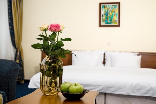 a vase with roses and apples on a table in a hotel room at Park Hotel Sankt Peterburg in Plovdiv