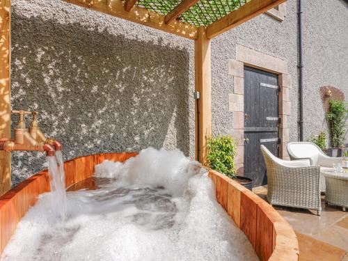 a tub filled with snow in a patio with a fountain at Westhills Courtyard - The Loft in Winster