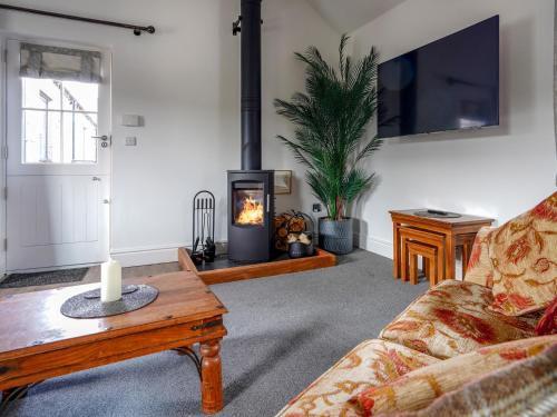 a living room with a couch and a fireplace at Westhills Courtyard - The Loft in Winster