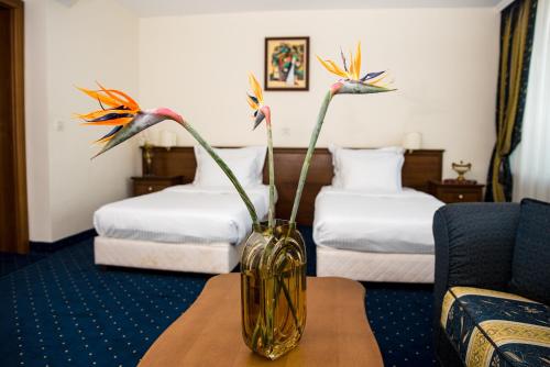a vase with flowers on a table in a hotel room at Park Hotel Sankt Peterburg in Plovdiv