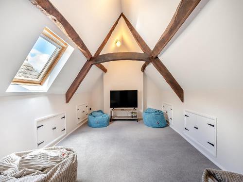 a attic room with a tv and a ceiling with beams at Greenhill Farmhouse in Bletchingdon