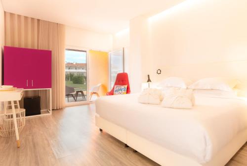 a white bedroom with a large white bed and a table at RIDE Surf Resort & Spa Peniche in Peniche