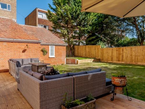 a patio with couches and an umbrella in a yard at West Bay House in Westgate-on-Sea