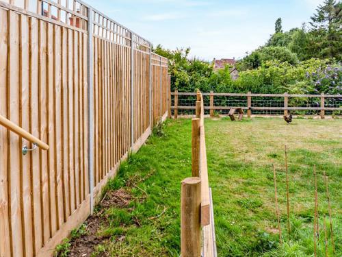 a wooden fence in a field with animals in the background at Fig Tree Shepherds Hut in Bridport