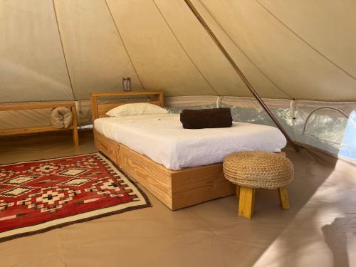 a bedroom in a tent with a bed and a stool at Eco-immersion in Limogne-en-Quercy