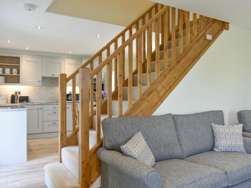 a living room with a couch and a wooden staircase at Deer Park Barn - Uk33323 in Reeth