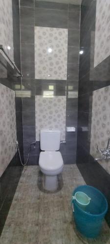 a bathroom with a toilet and a blue bucket at Steep Valley Resort in Kotagiri