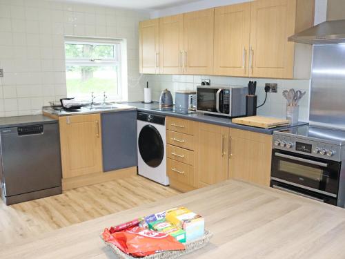 a kitchen with wooden cabinets and stainless steel appliances at Gate House in Llangefni