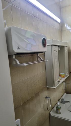 a bathroom with a sink and a light on the wall at Quarto suite 1 dorm Prox da Casa de Saude mais salas e estacionamento in Santa Maria