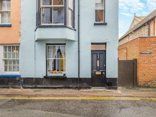 a white house with a black door on a street at Melrose Cottage in Cromer