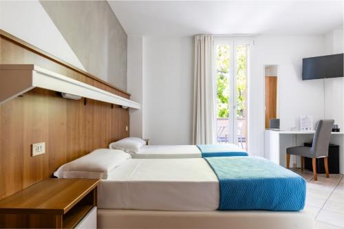 zwei Betten in einem Zimmer mit Schreibtisch und Tisch in der Unterkunft Hotel EMI in Calderara di Reno