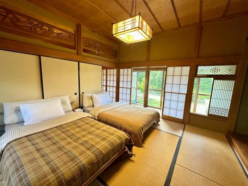 two beds in a room with windows and a chandelier at 館山ガーデンヴィラ 宮城ハウス - 平屋一棟貸し 屋根付きBBQ ペットok in Tateyama