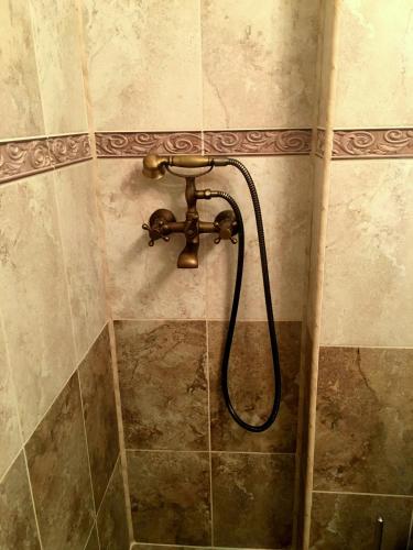 a shower with a hose attached to a tiled wall at Amy's Studio in Bucharest